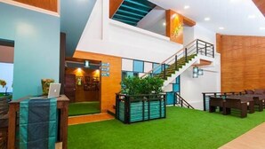 A modern interior with a staircase, seating area, and a reception desk. - Aukotan Place Hotel (Koh Tao)