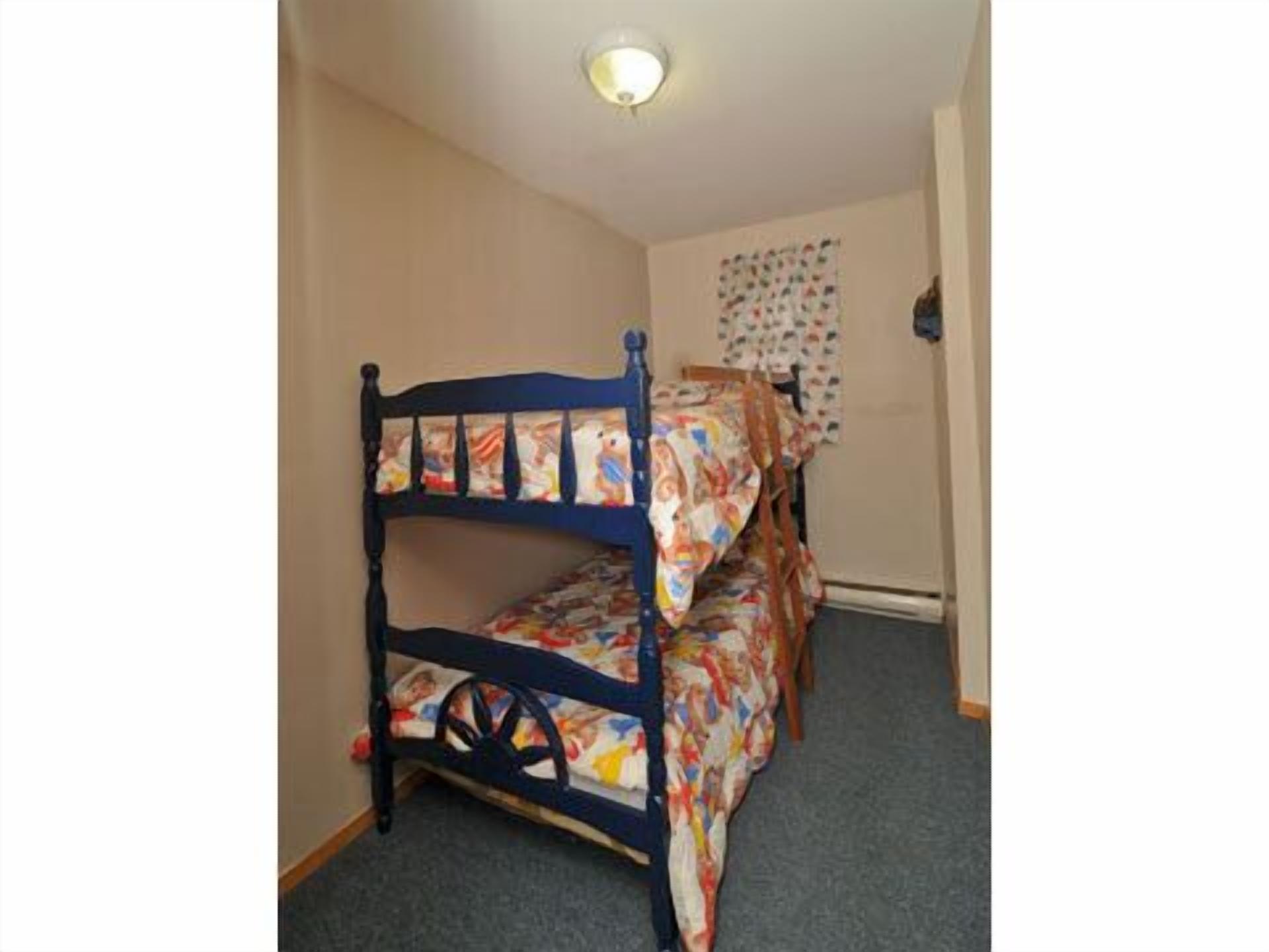 A bunk bed with a headboard featuring a stained glass design, a wooden frame, and a mattress with a colorful pattern.