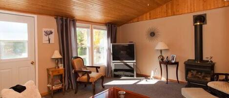 A cozy living room with a wooden ceiling, a television, a fireplace, and a comfortable seating area.