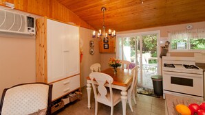 A wooden-paneled kitchen with a dining table, chairs, a chandelier, and a stove.