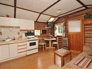 Una habitación acogedora de estilo cabaña con cocina, comedor y sofá.