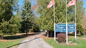 A pathway leading to North Shore Cottages with flags, a signboard, and a clear sky.