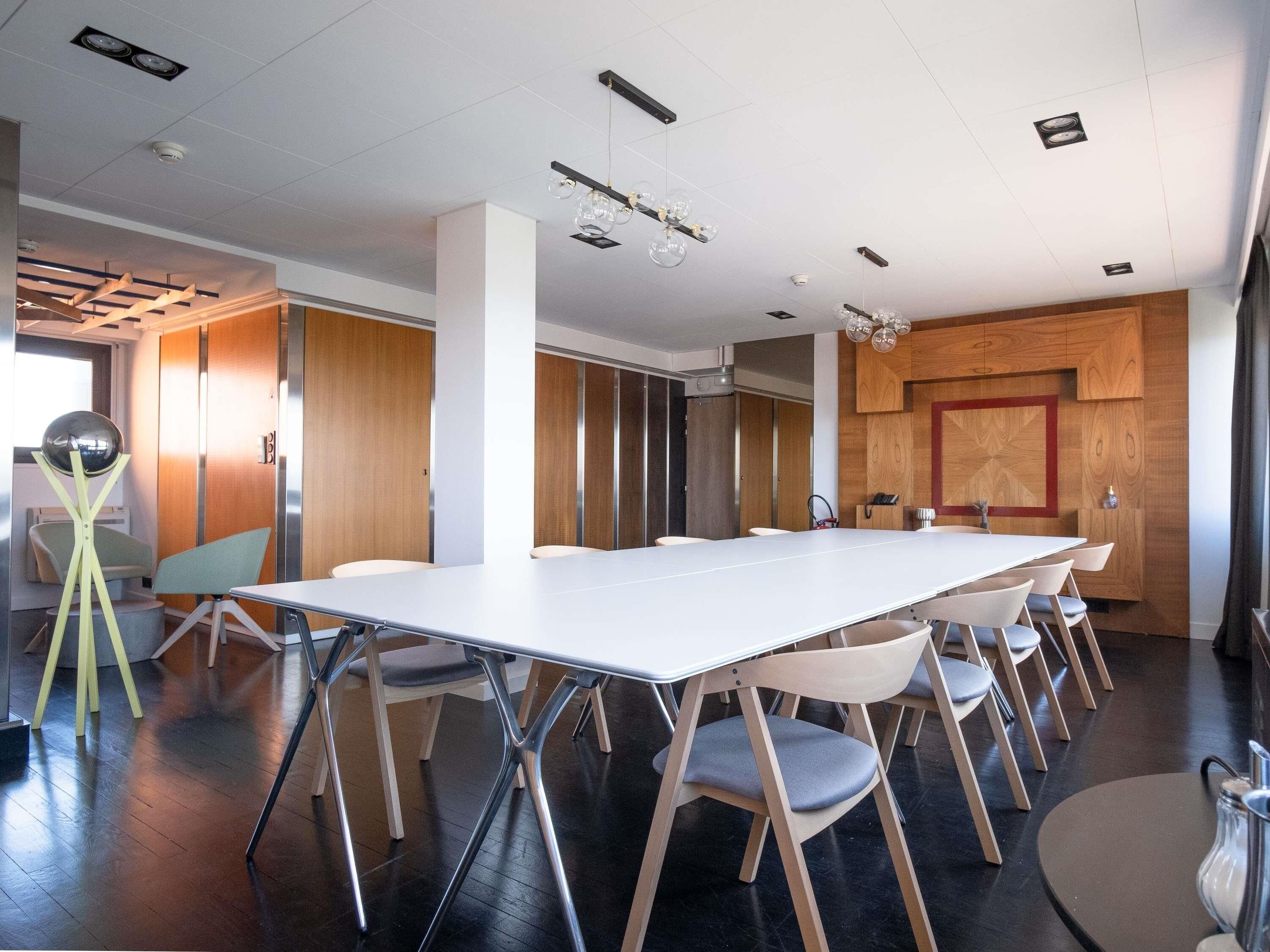 A conference room with a long table, chairs, and a modern ceiling design.