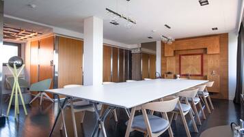 Un salón de conferencias con una larga mesa, sillas y un diseño moderno en el techo.