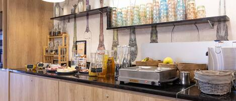 Una encimera de cocina con varios recipientes de vidrio, una cafetera y una cesta de frutas.