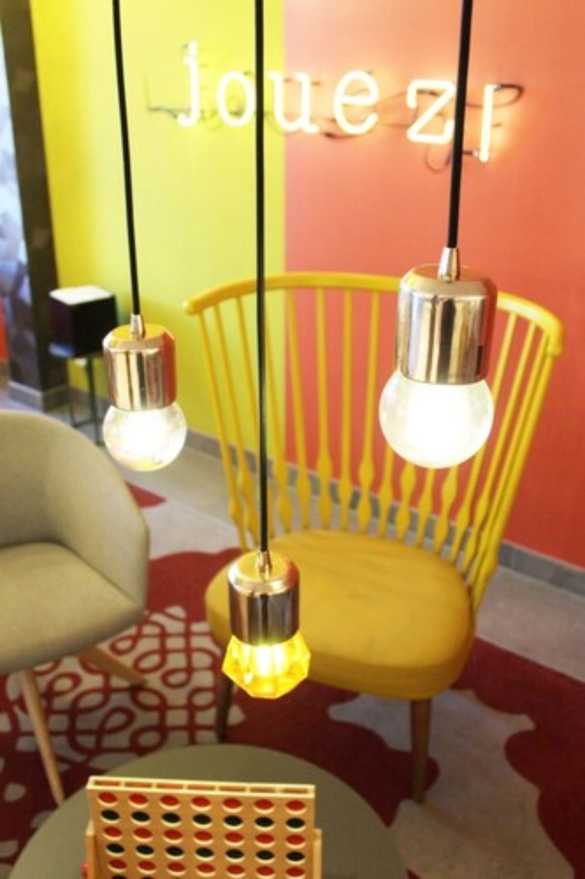 Una silla amarilla de diseño moderno, una mesa redonda y una pared con un letrero de neón.