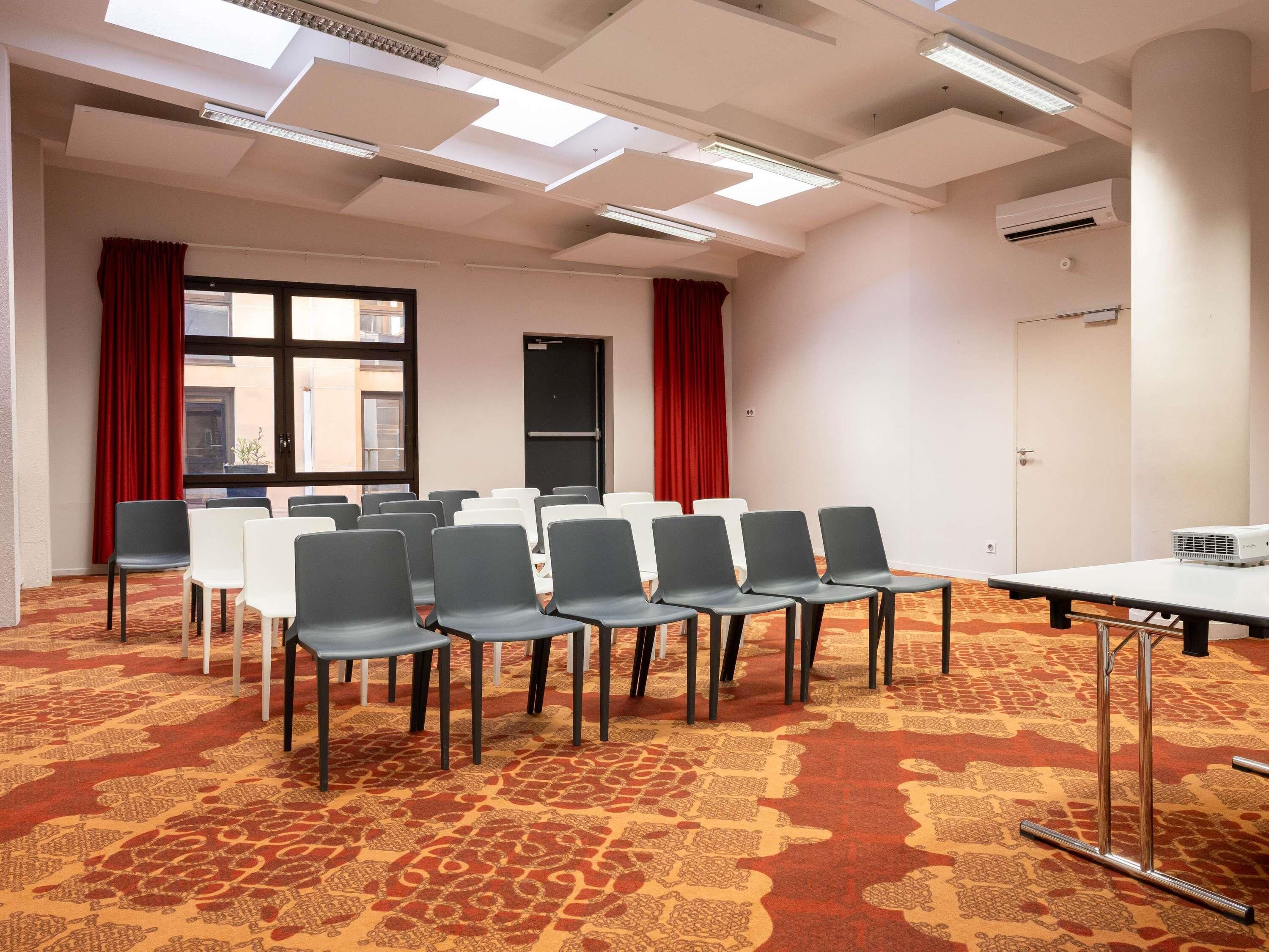 Una sala de conferencias con piso alfombrado, un proyector y una mesa.