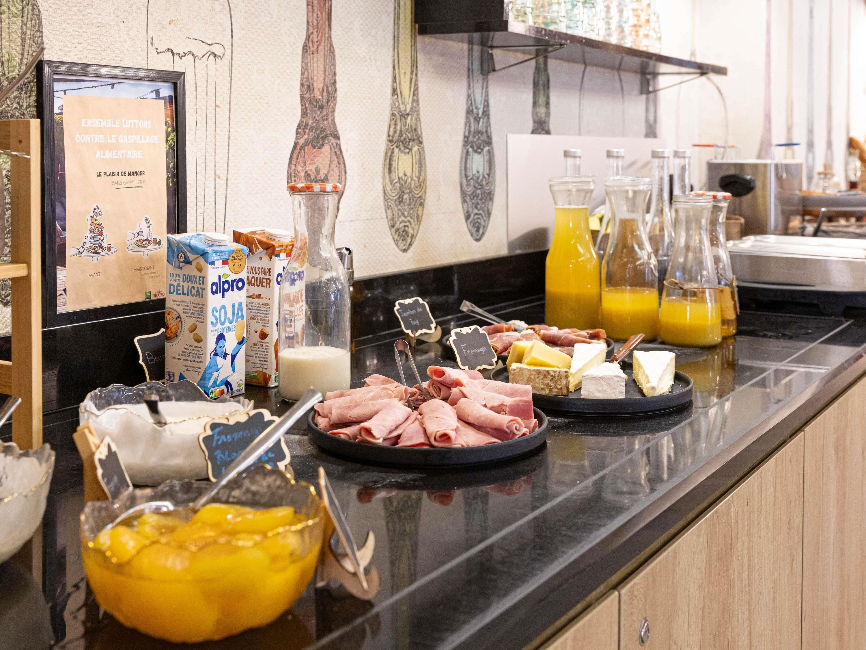 Un buffet proposant une variété de plats, notamment des viandes, des fromages et un saladier de salade de fruits.
