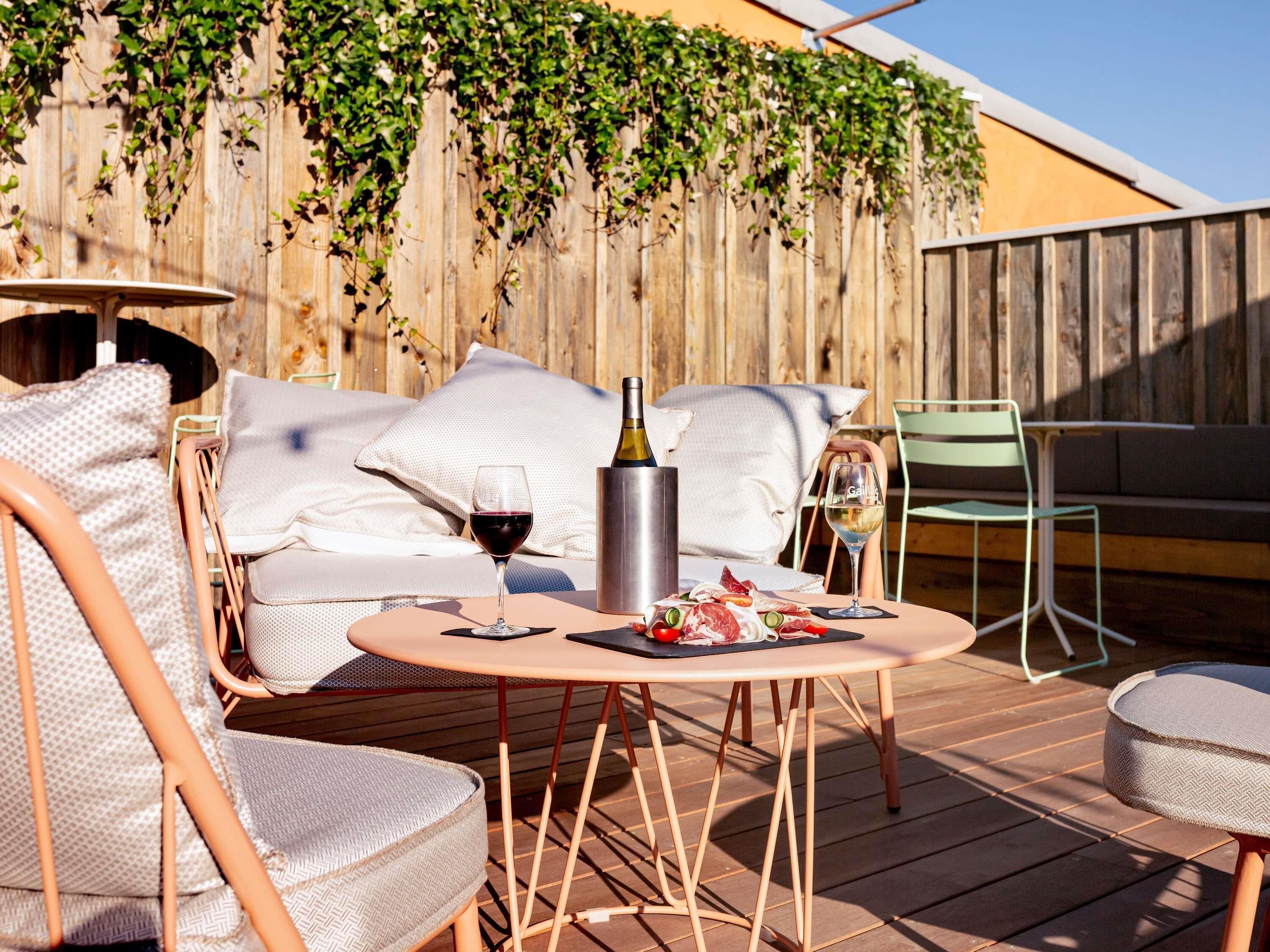 Un espace extérieur aménagé avec une table, des chaises, une bouteille de vin et un verre de vin.