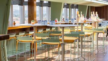 A restaurant with outdoor seating, tables, chairs, and a view through large windows.