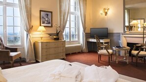 Een hotelkamer met een bed, een bureau, een televisie en een open haard.