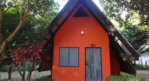 A small, orange building with a triangular roof, a door, and two windows.