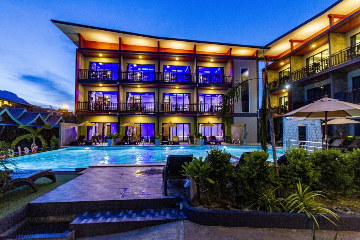 Un hôtel à plusieurs étages doté d’une piscine, d’un espace extérieur aménagé et de balcons.