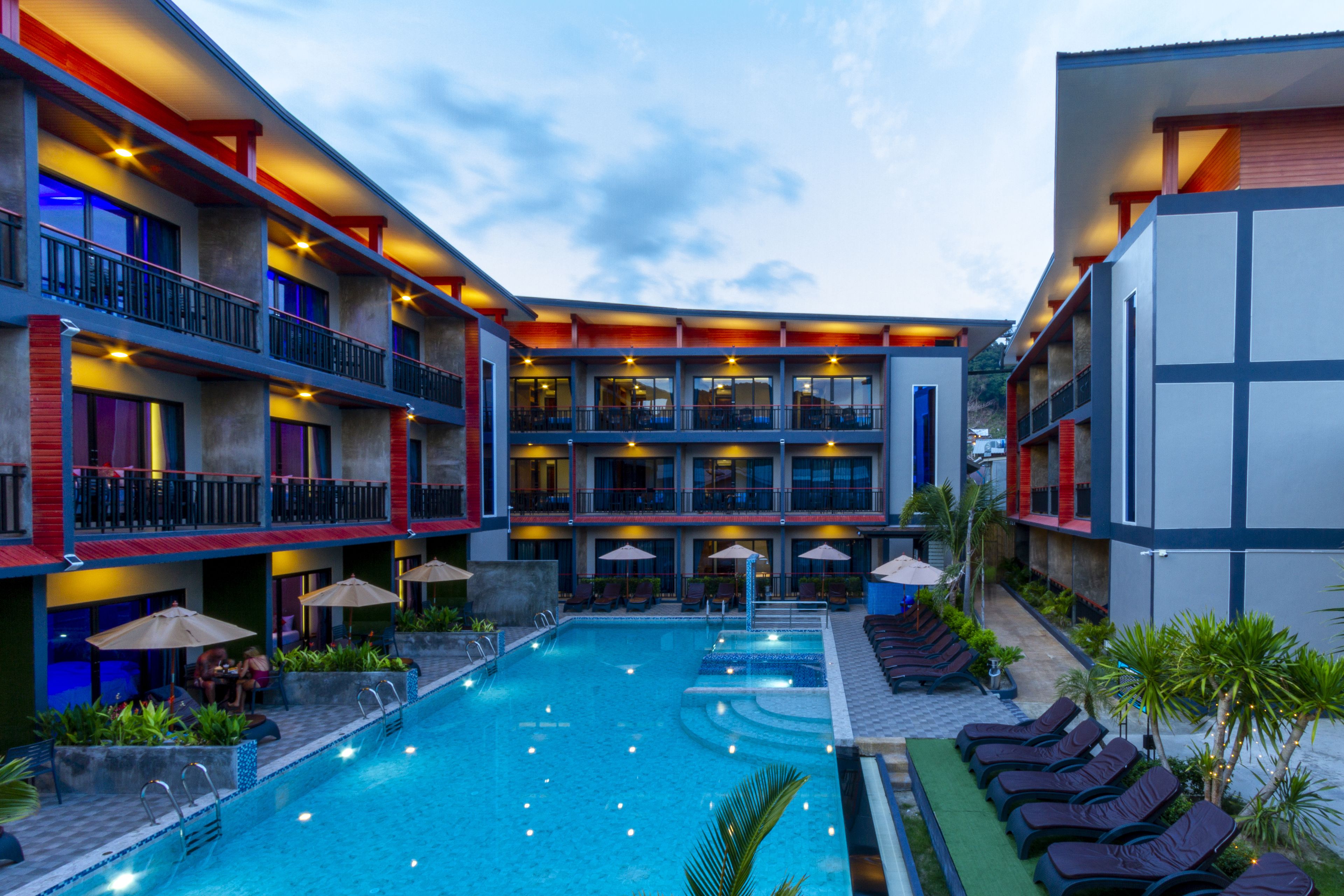 A hotel with a swimming pool, multiple balconies, and outdoor seating areas.