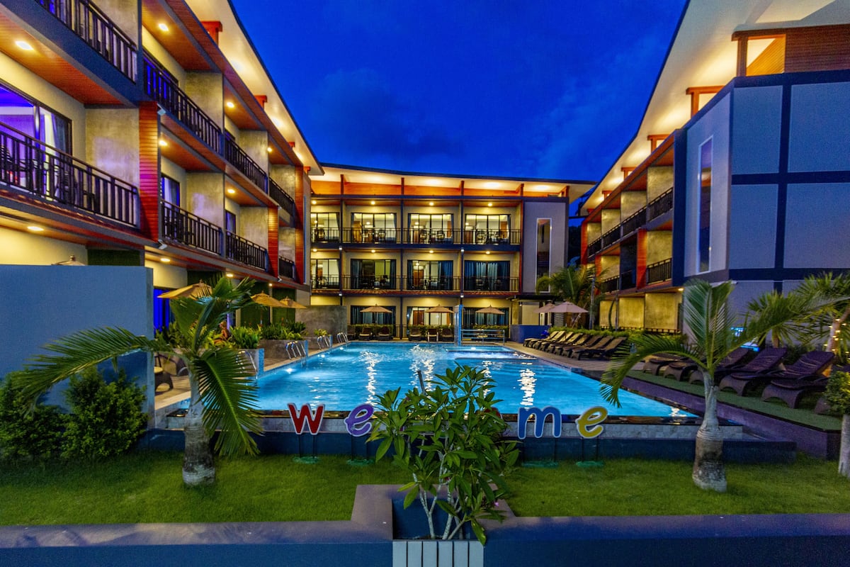 Un hôtel doté d’une piscine, de plusieurs balcons et d’une façade bien éclairée.