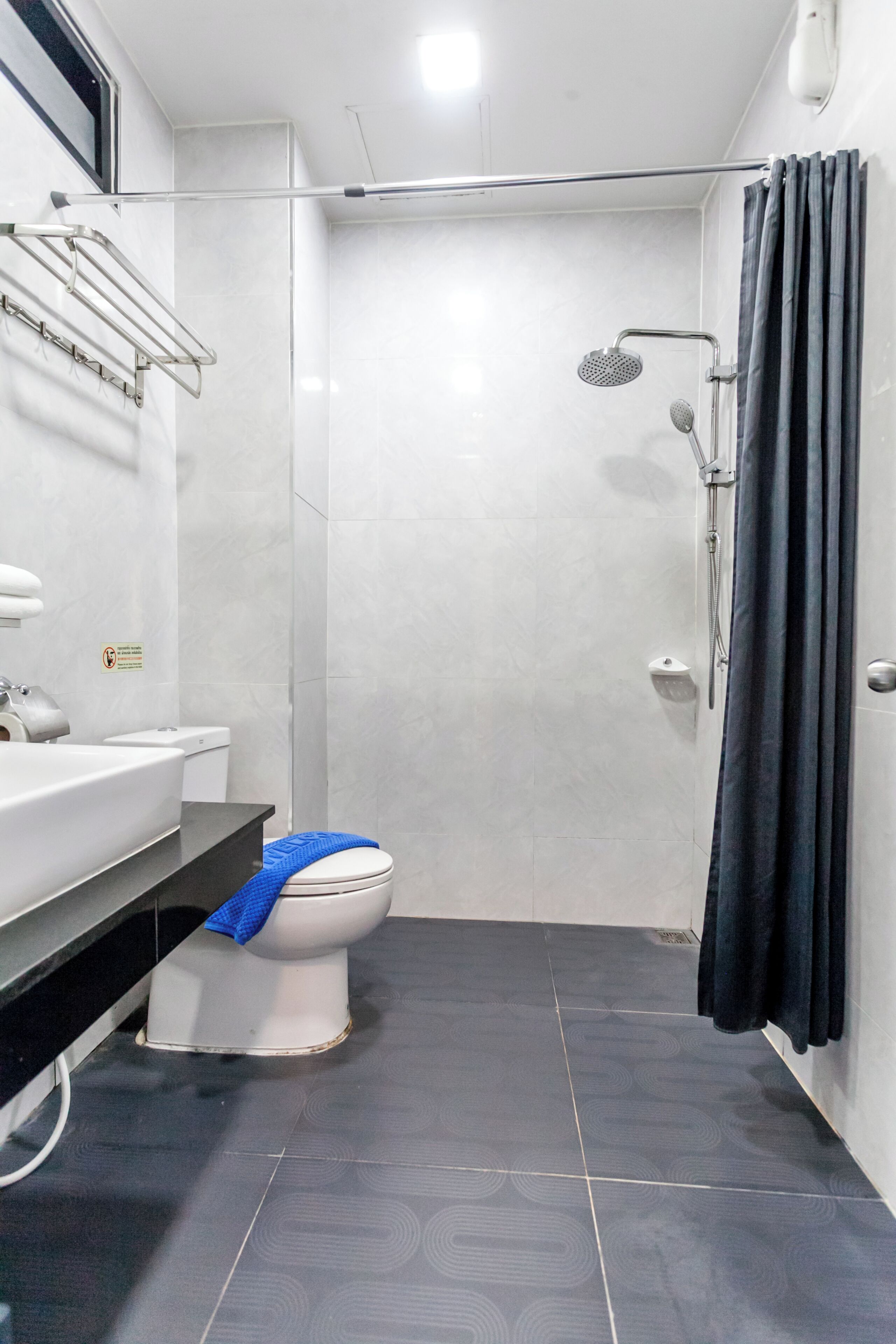 A bathroom with a white toilet, a sink, a shower with a curtain, and tiled walls.