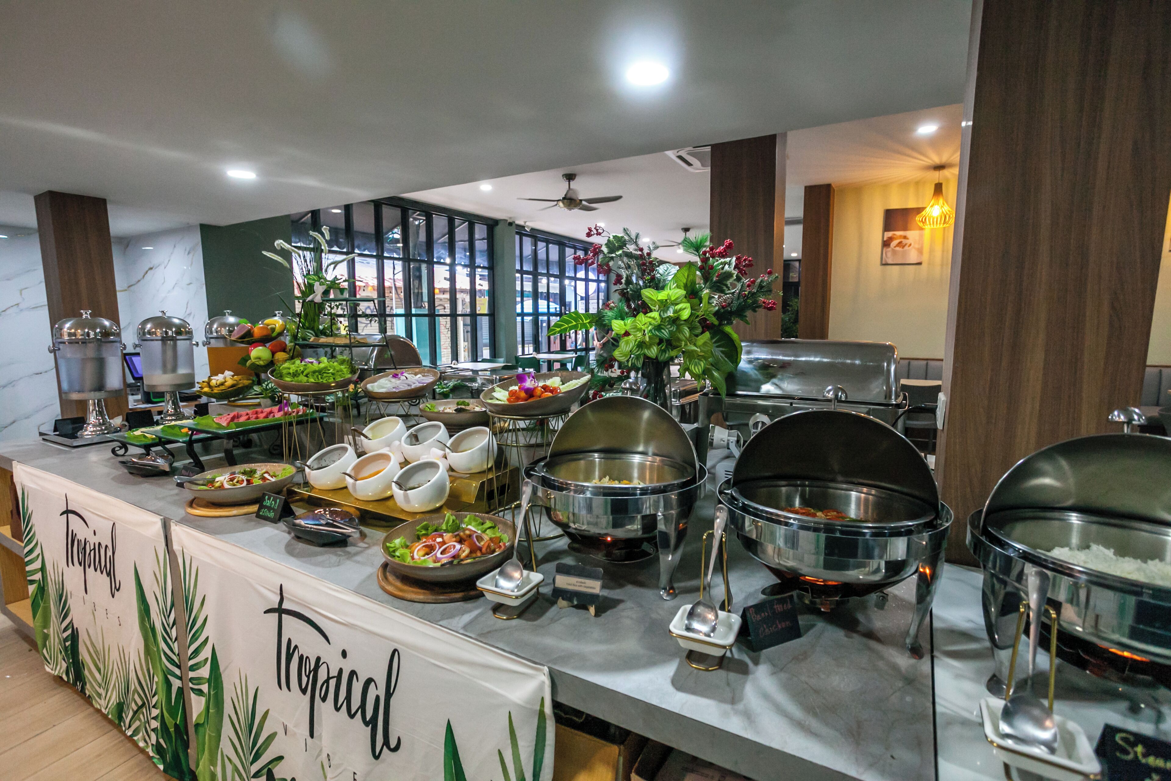 A buffet with various food items and a tropical-themed sign.
