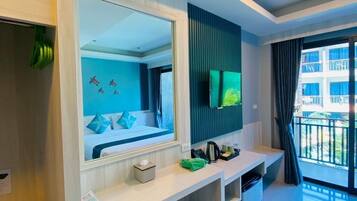 Une chambre d’hôtel moderne dotée d’un grand miroir, d’un téléviseur à écran plat, d’un petit bureau, d’une poubelle et d’un balcon offrant une vue sur la ville.