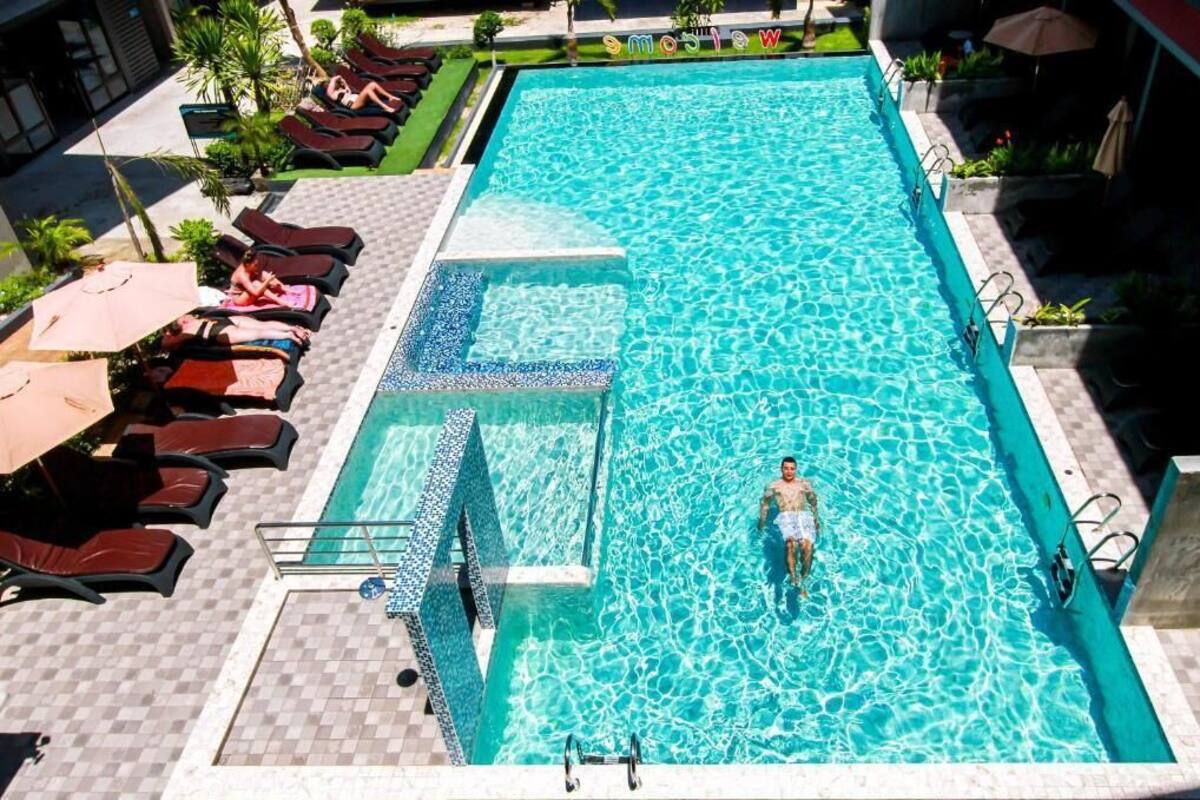 Une piscine rectangulaire avec une zone de terrasse carrelée, des chaises longues et des parasols.