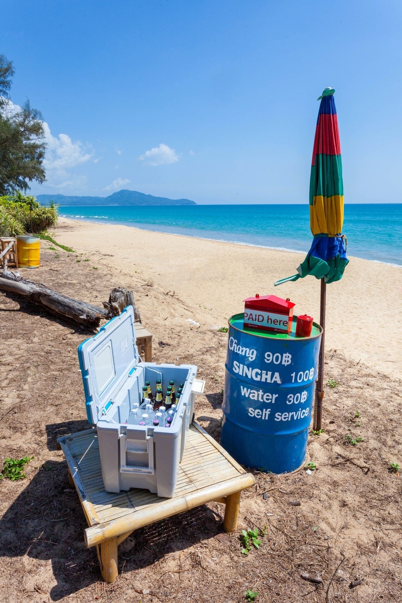 A beach setup with a cooler, a water barrel, and a beach chair.