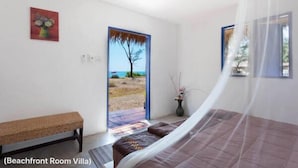Habitación frente a la playa con cama, banco y puerta que da a vistas de la playa.