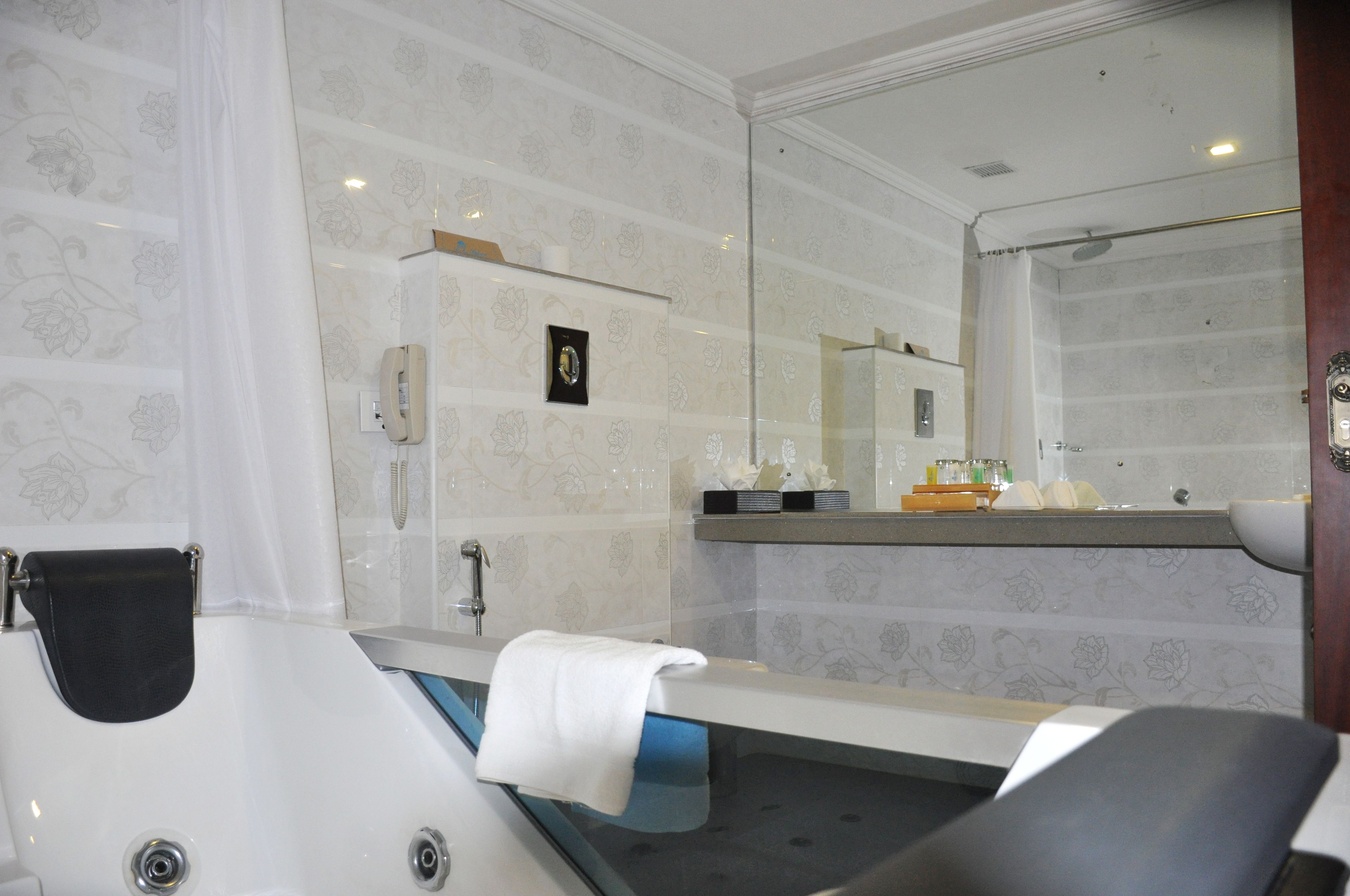 Un baño con bañera, lavamanos y un espejo grande.