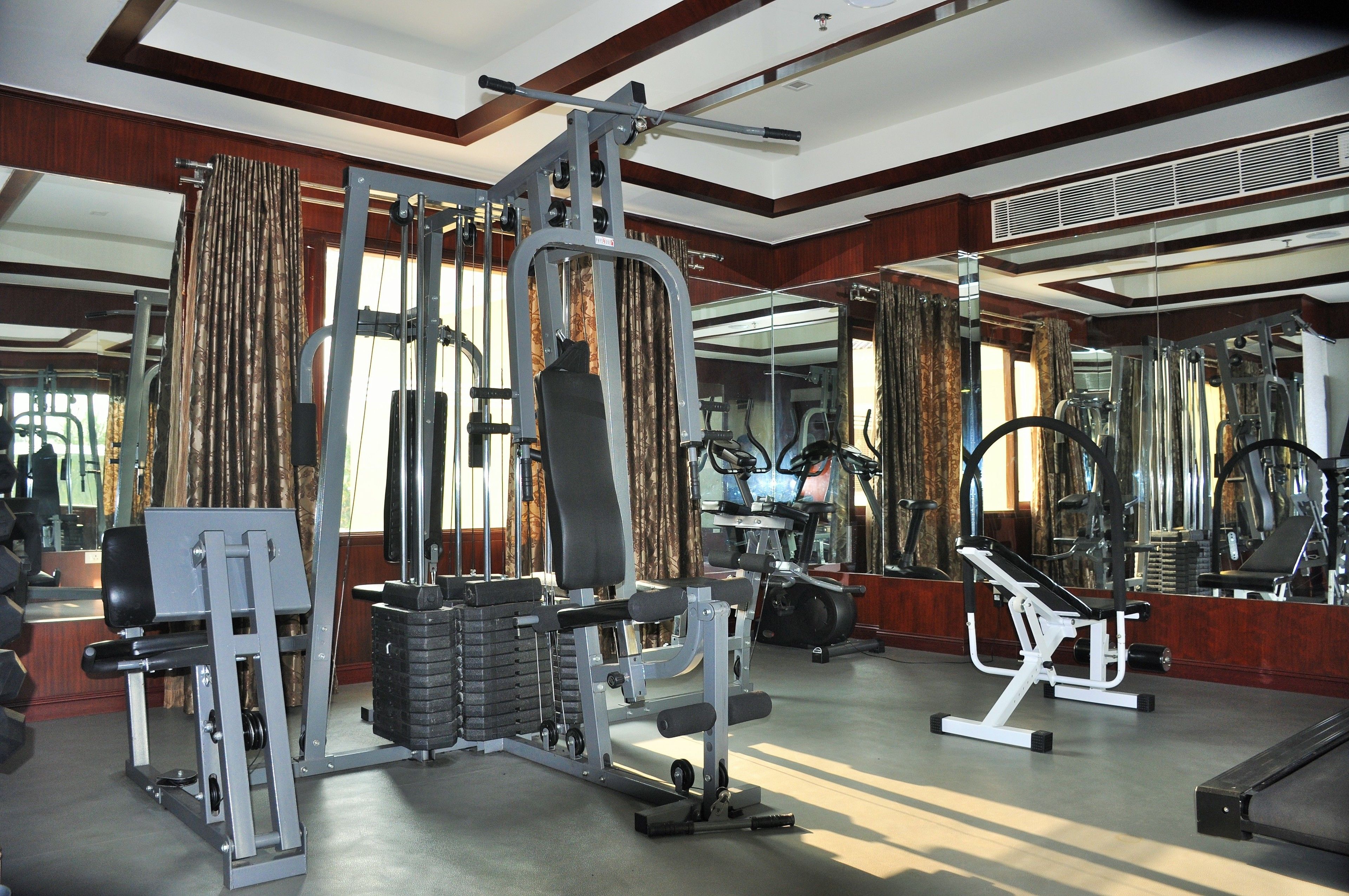 A gym with various exercise equipment, large mirrors, and a wooden interior.