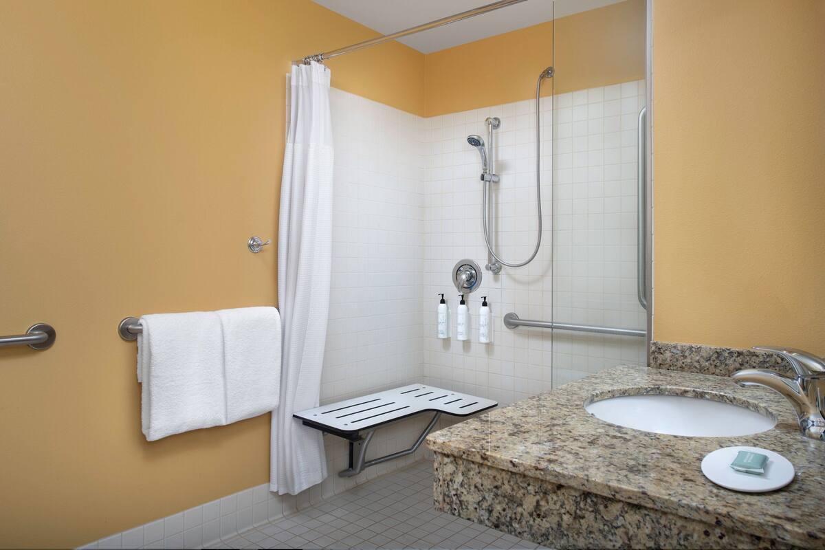 Une salle de bain avec une douche, un lavabo et un porte-serviettes.
