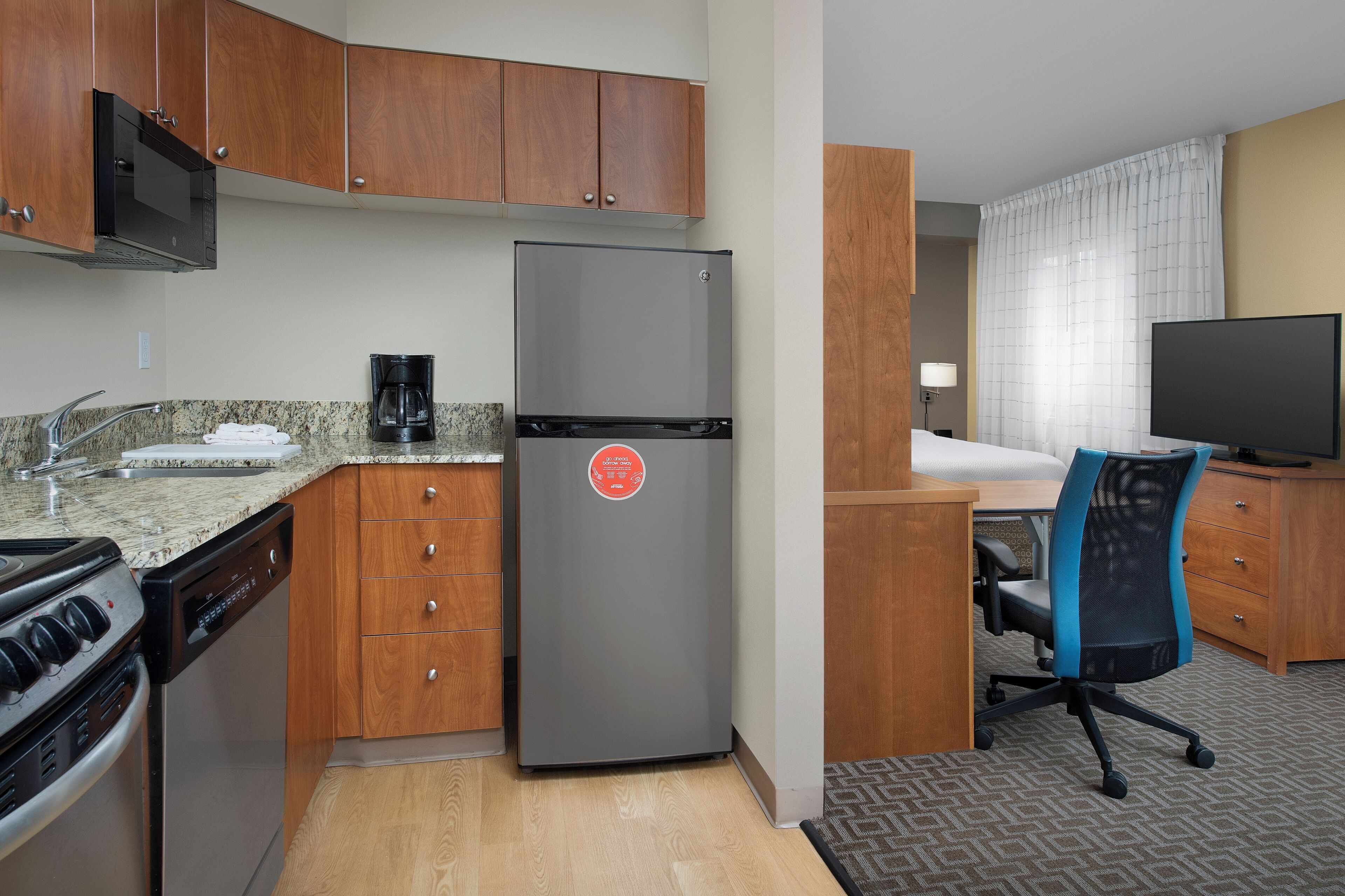 A compact kitchen with a refrigerator, stove, and coffee maker.