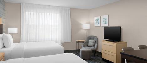 Une chambre d’hôtel avec deux lits, une télévision, un bureau et une chaise.