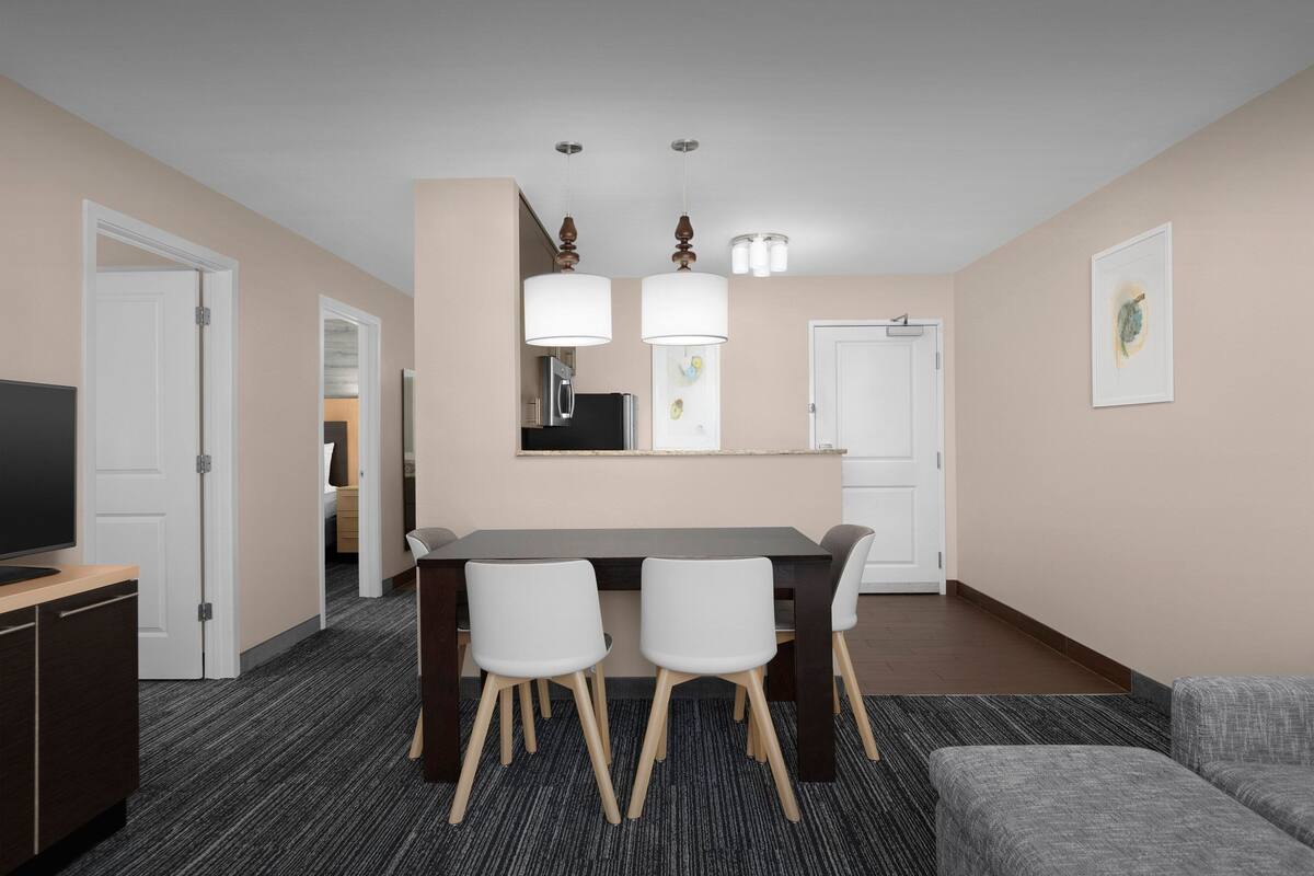 Una habitación de hotel moderna con comedor, televisión y sofá.