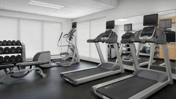 A gym with treadmills, elliptical machines, and a bench press.