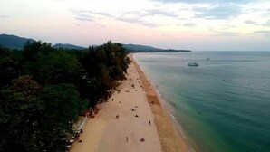 A beach with people and boats, surrounded by trees and hills. - Lanta Sunny House (Ko Lanta)