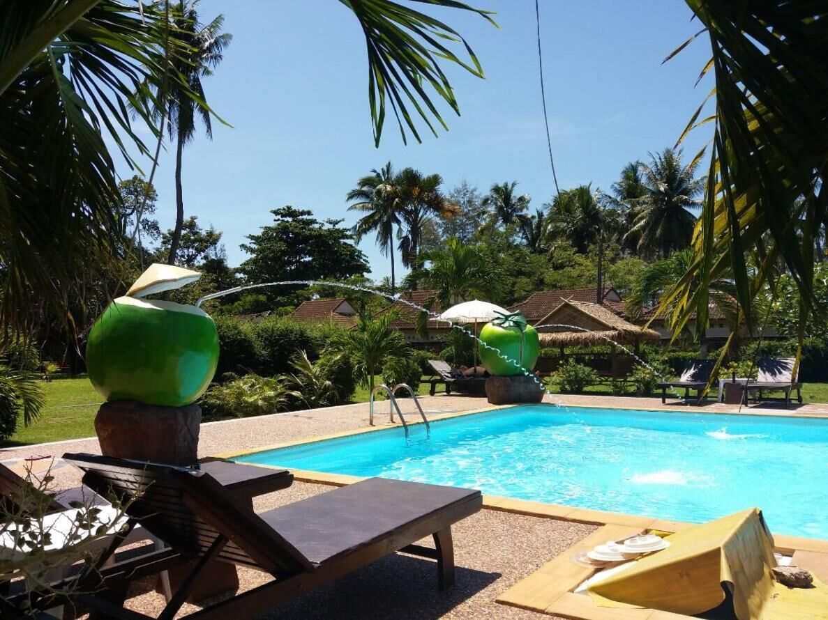 A pool area with lounge chairs, a clear blue pool, and tropical vegetation.