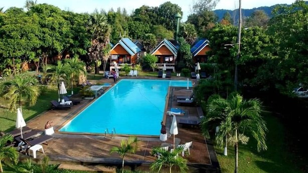 A resort with a swimming pool, lounge chairs, and palm trees. - Lanta Sunny House (Ko Lanta)