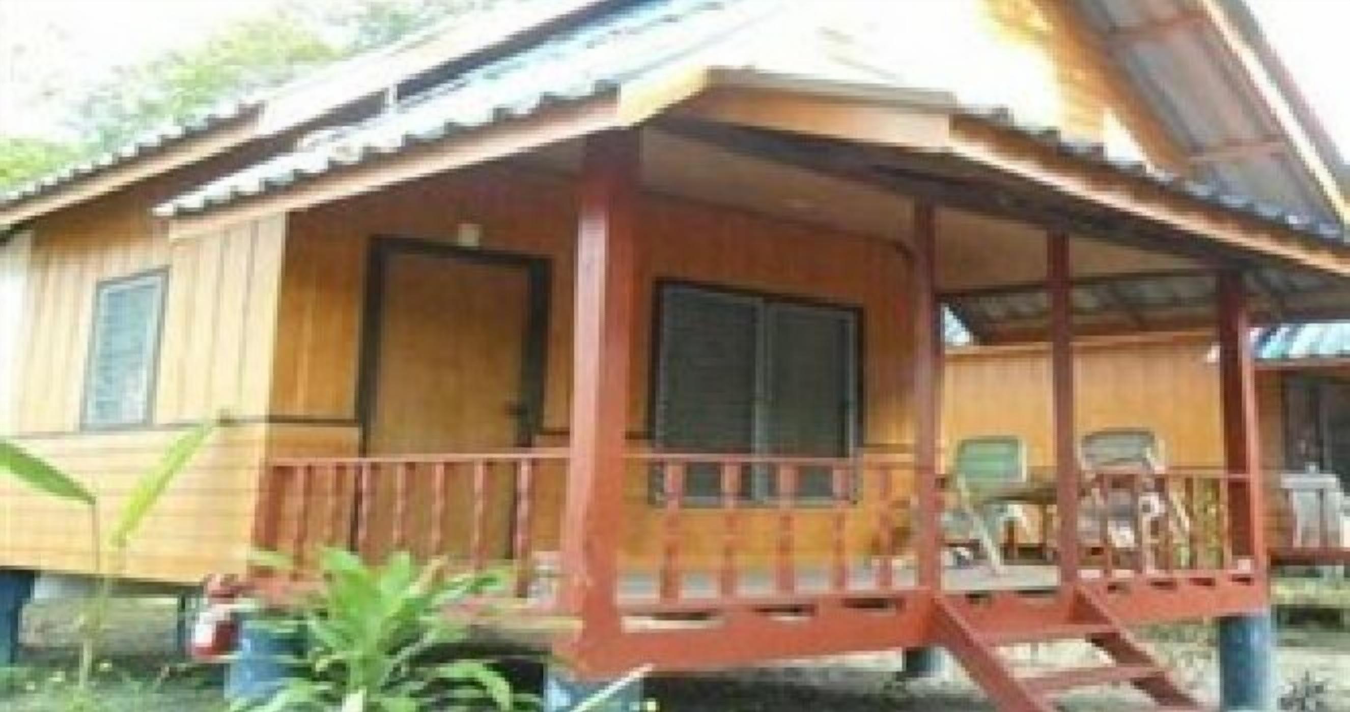 A wooden house with a porch, windows, and a door.