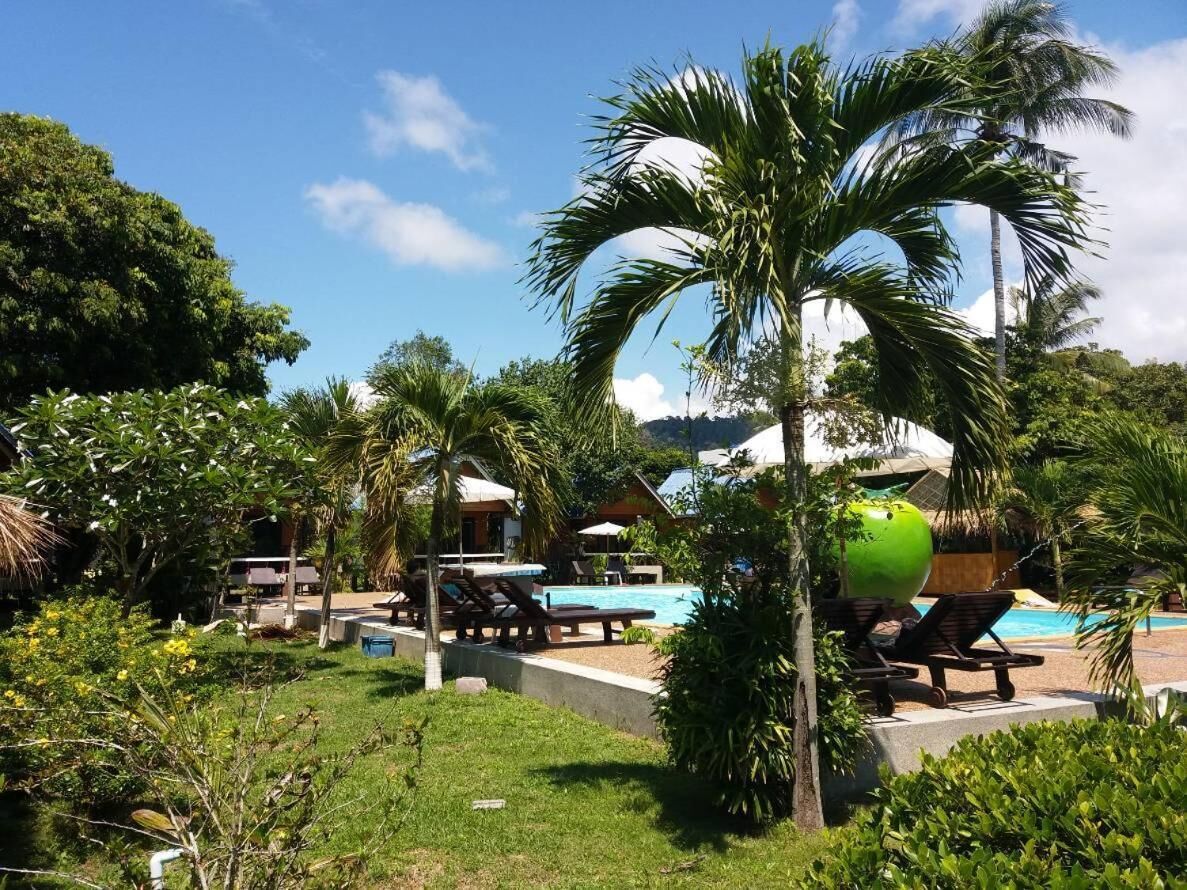 Ein Resort mit Poolbereich, Liegestühlen und Palmen.