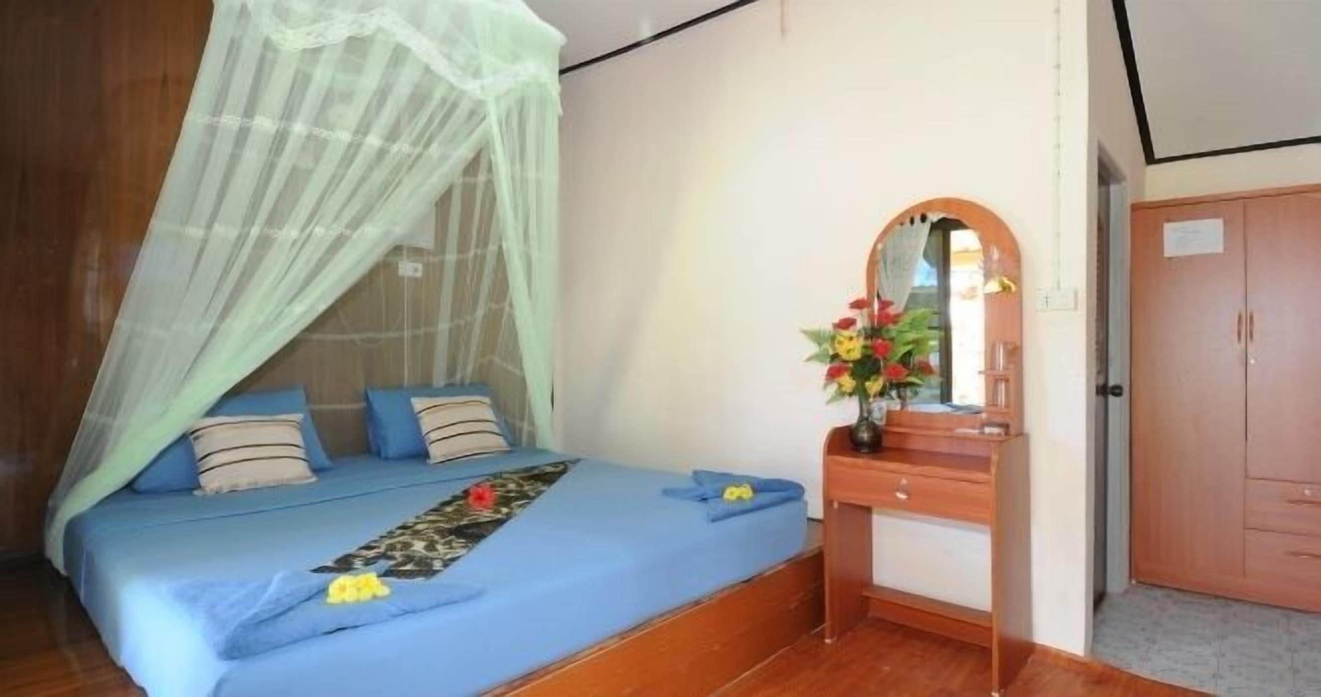 Een slaapkamer met een bed, een houten dressoir, een spiegel en een kledingkast.
