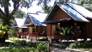 A row of wooden cabins with metal roofs, surrounded by lush greenery and trees. - Lanta Sunny House (Ko Lanta)