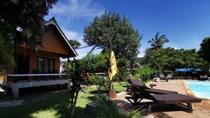 A resort with a swimming pool, lounge chairs, and a covered area with umbrellas. - Lanta Sunny House (Ko Lanta)