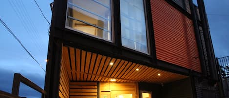 A building with a reception area, wooden slats on the facade, and a red vehicle parked outside.
