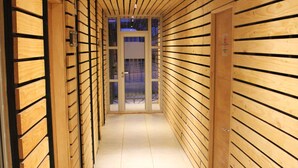 A corridor with wooden paneling and tiled flooring, leading to a glass door at the end. - Apart Hotel Quillango (Punta Arenas)