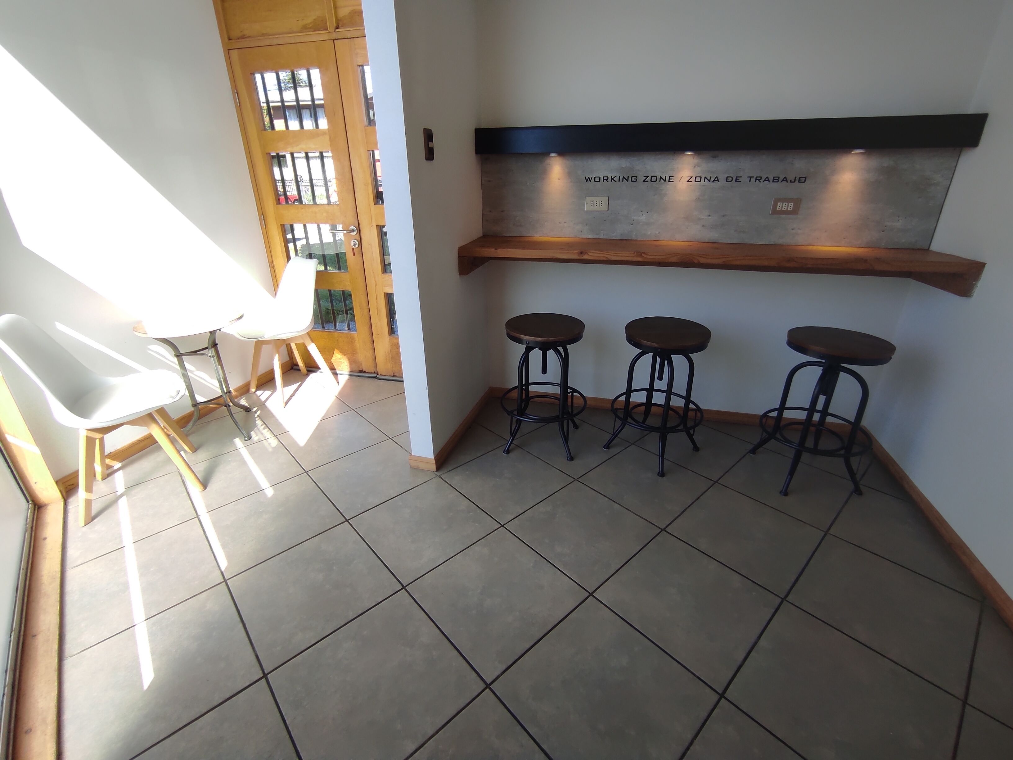 A kitchen area with a wooden door, a white chair, and three stools.