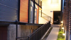 A narrow pathway leading to a building with a metal railing and a brick wall on one side. - Apart Hotel Quillango (Punta Arenas)