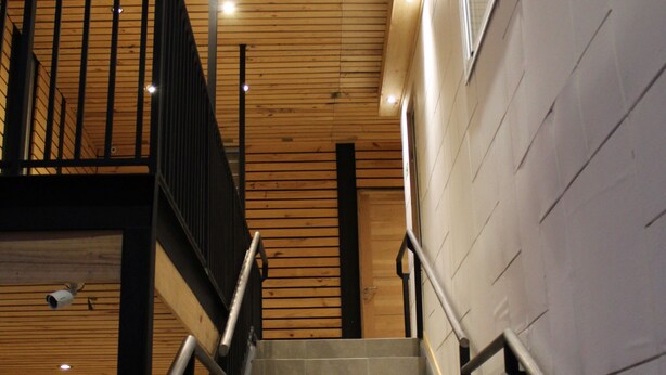 A staircase with wooden paneling and metal railings, leading to an upper level. - Apart Hotel Quillango (Punta Arenas)