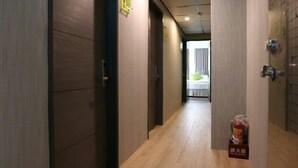 A hotel corridor with wooden flooring and doors, leading to a room with a bed and a window. - TO Hotel Chengde (Taipei)
