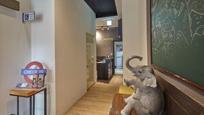 A hotel hallway with a check-in counter, a sign for a disabled toilet, and a decorative elephant sculpture. - TO Hotel Chengde (Taipei)