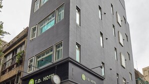 A T.O. Hotel with a modern design, featuring a grey facade, multiple windows, and a visible entrance. - TO Hotel Chengde (Taipei)