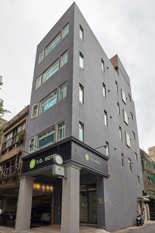 A T.O. Hotel with a modern design, featuring a grey facade, multiple windows, and a visible entrance. - TO Hotel Chengde (Taipei)