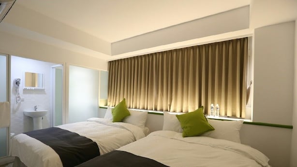 A hotel room with two beds, a window with curtains, a sink, and a mirror. - TO Hotel Chengde (Taipei)
